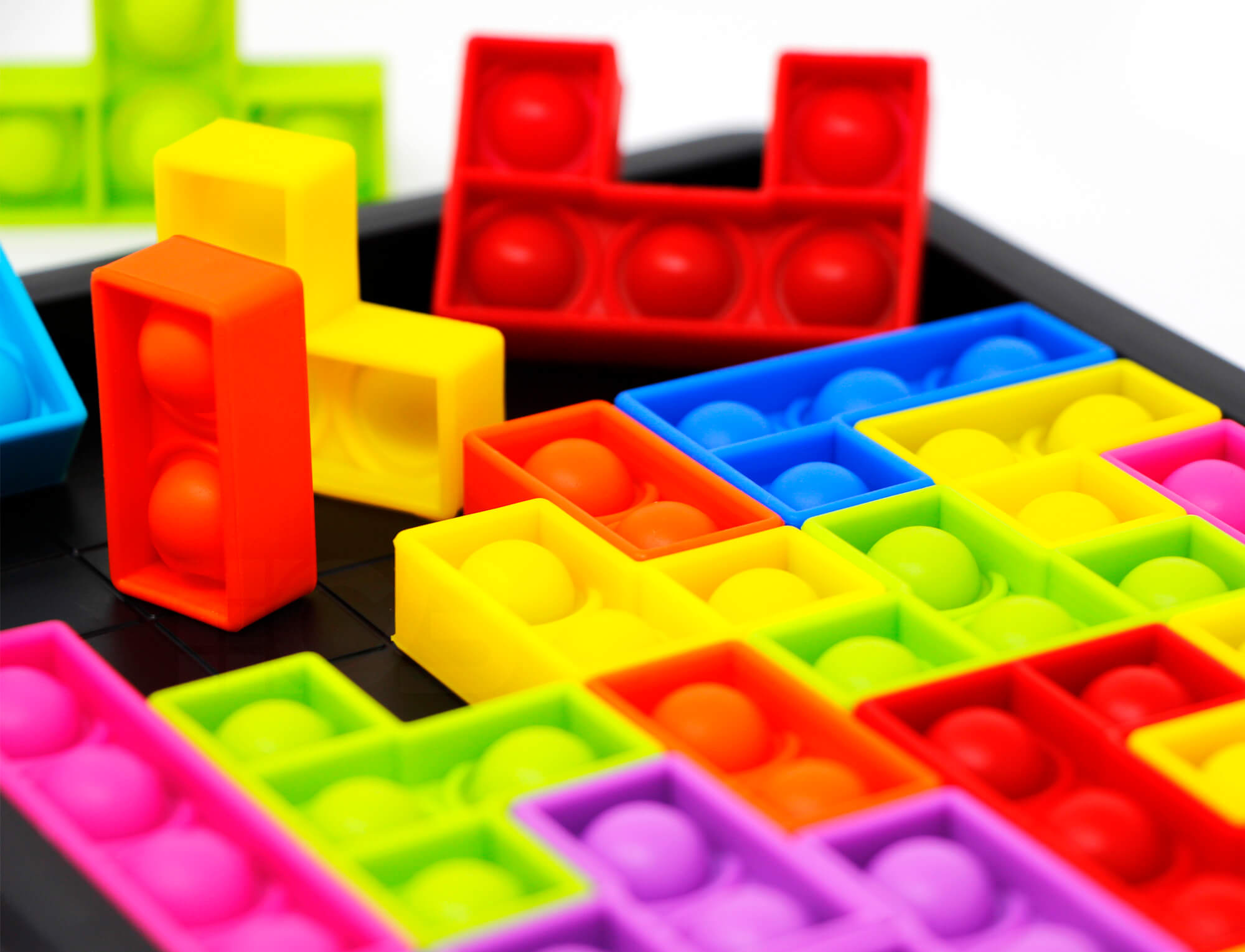 Criança encaixando peça colorida de silicone no tabuleiro do jogo Blocks Tetris Pop It